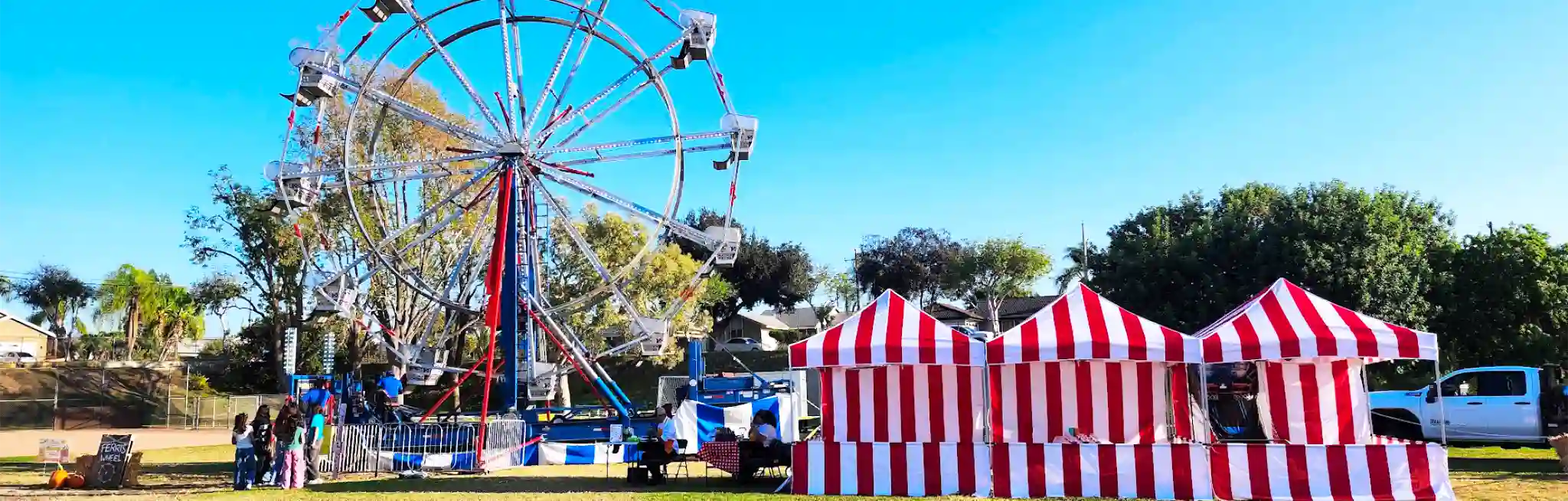 An event planned by Zebra Entertainment featuring a Ferris Wheel and multiple red and white striped circus tents.